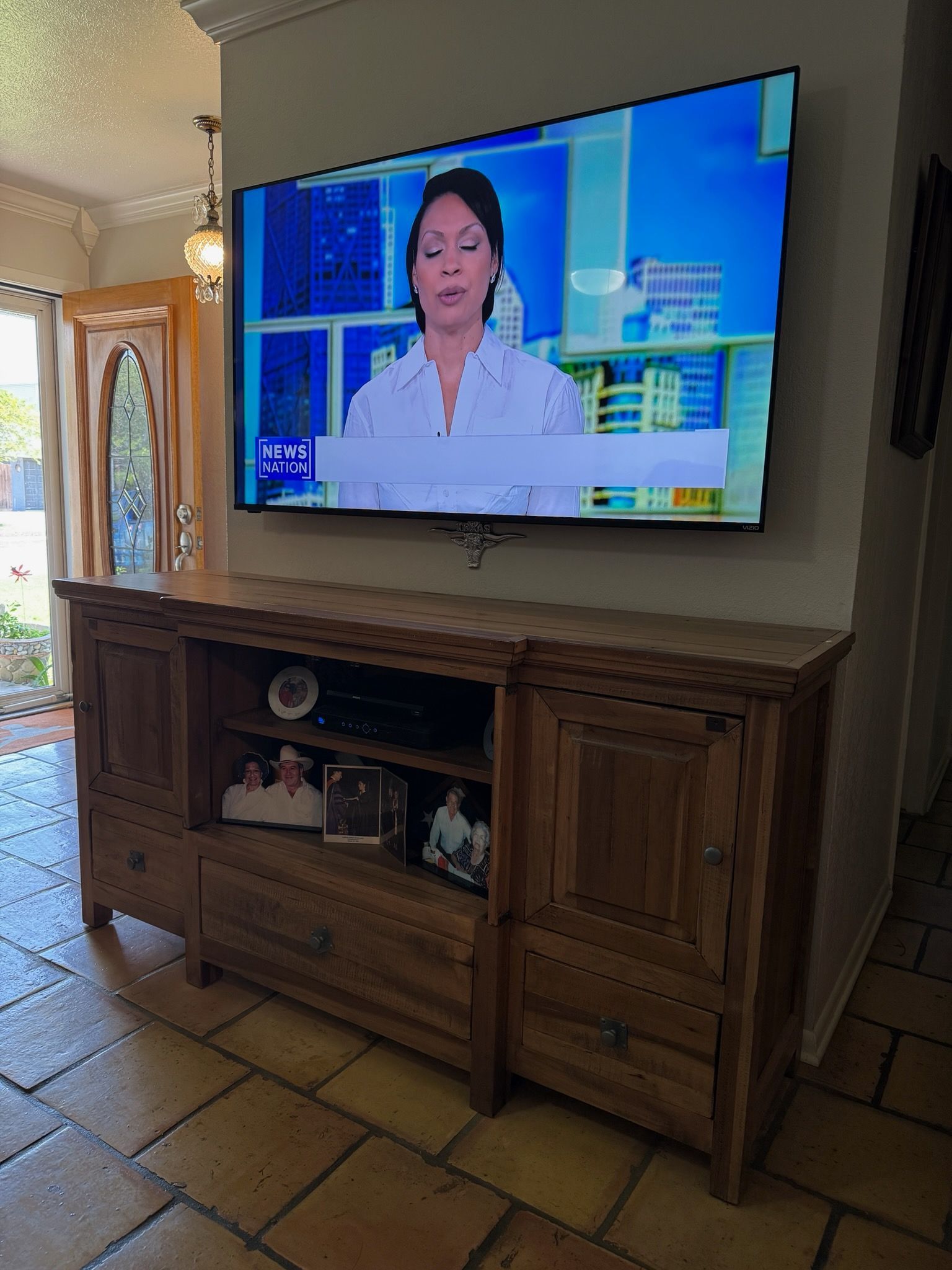 A large flat screen tv is hanging on a wall above a wooden entertainment center.