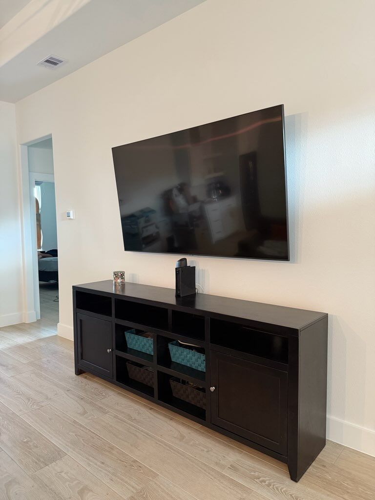 A living room with a flat screen tv mounted on the wall above a black entertainment center.