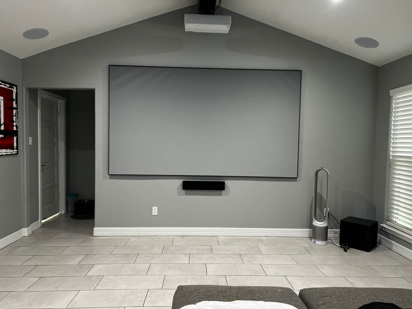 A living room with a large screen on the wall.