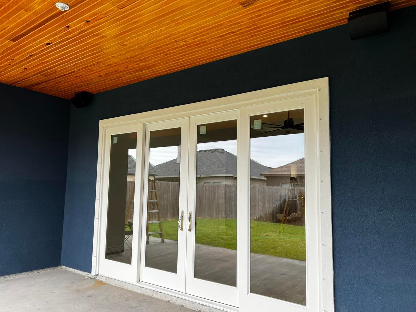 A blue house with white sliding glass doors and a wooden ceiling.