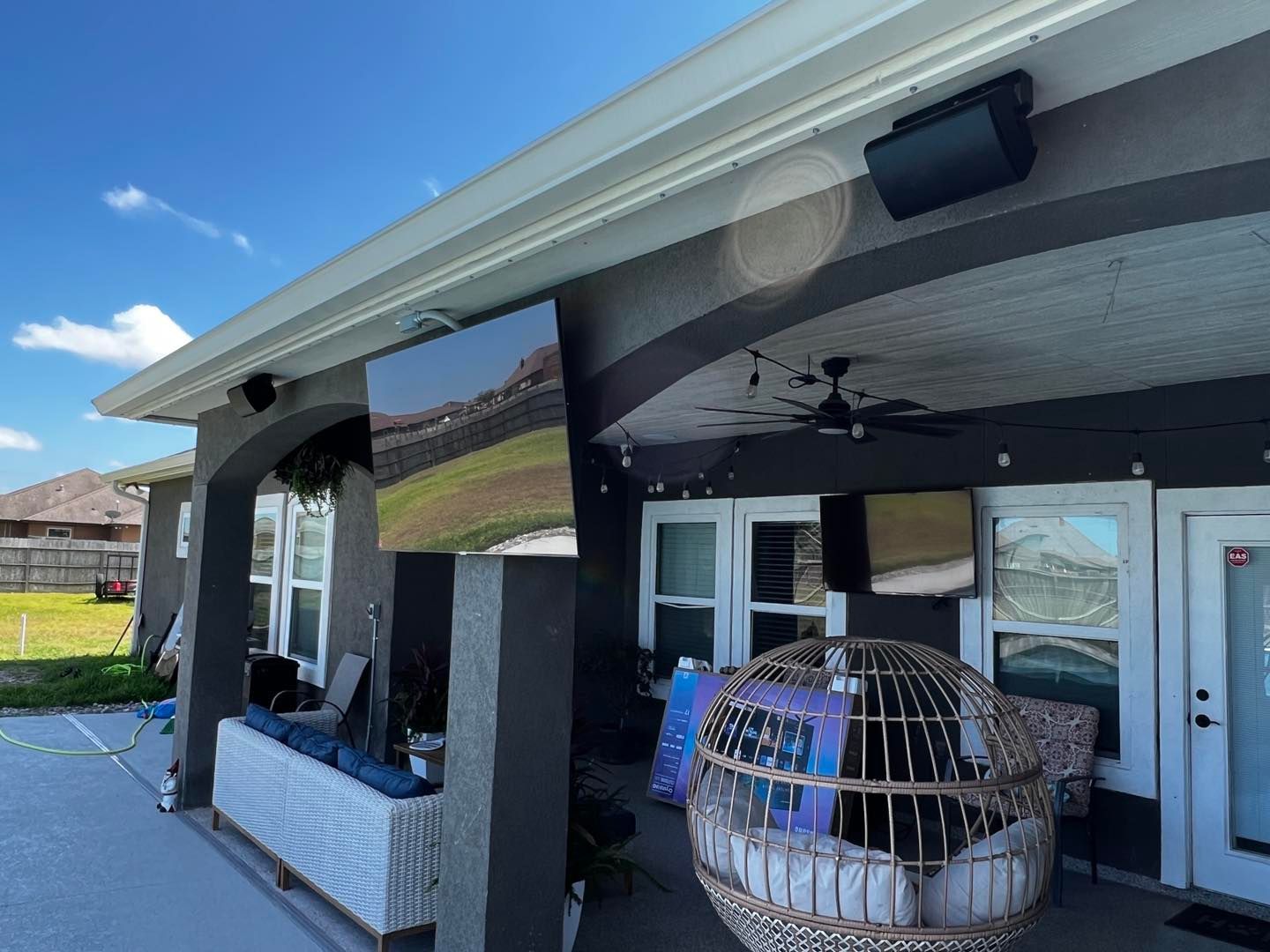 A patio with a wicker chair and a large flat screen tv