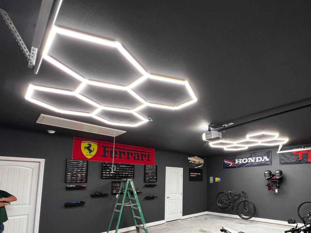 A man is standing on a ladder in a garage with a ferrari sign on the wall.