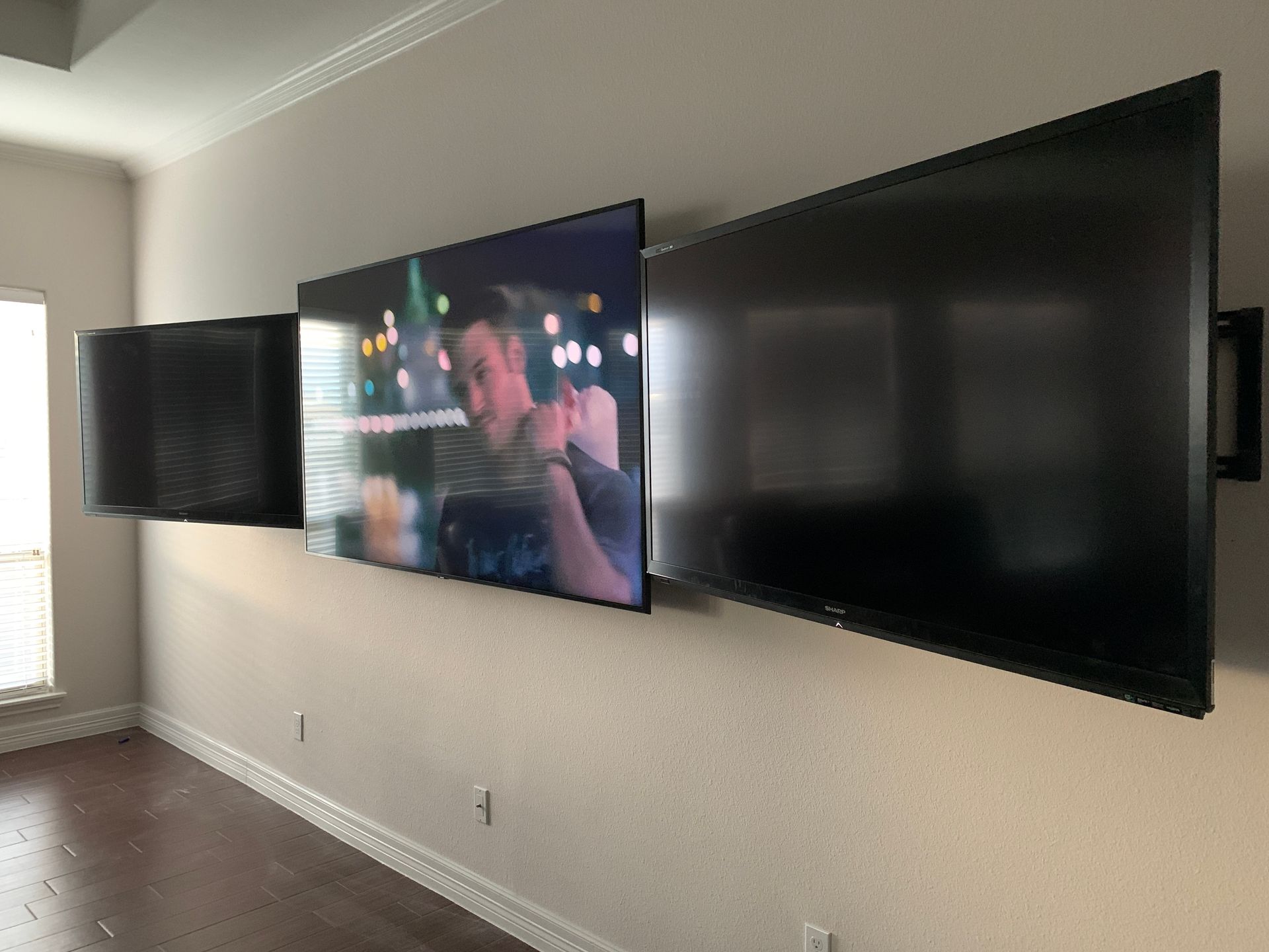 Two flat screen televisions are mounted on a wall in a living room.