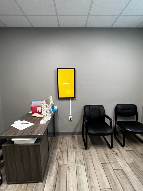 A waiting room with a desk and chairs and a yellow sign on the wall.