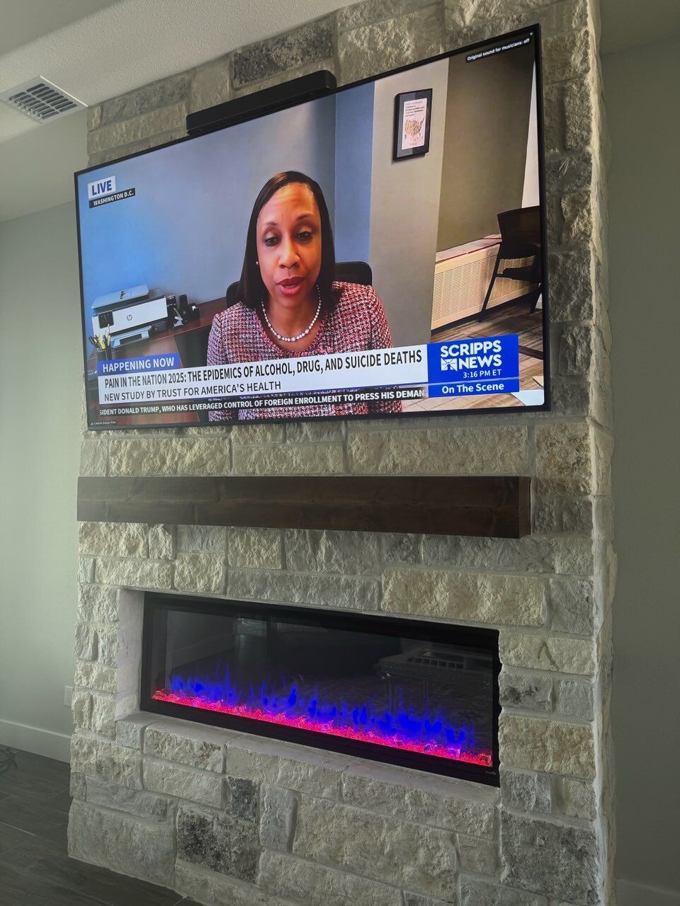 A flat screen tv is hanging on a brick wall above a fireplace.