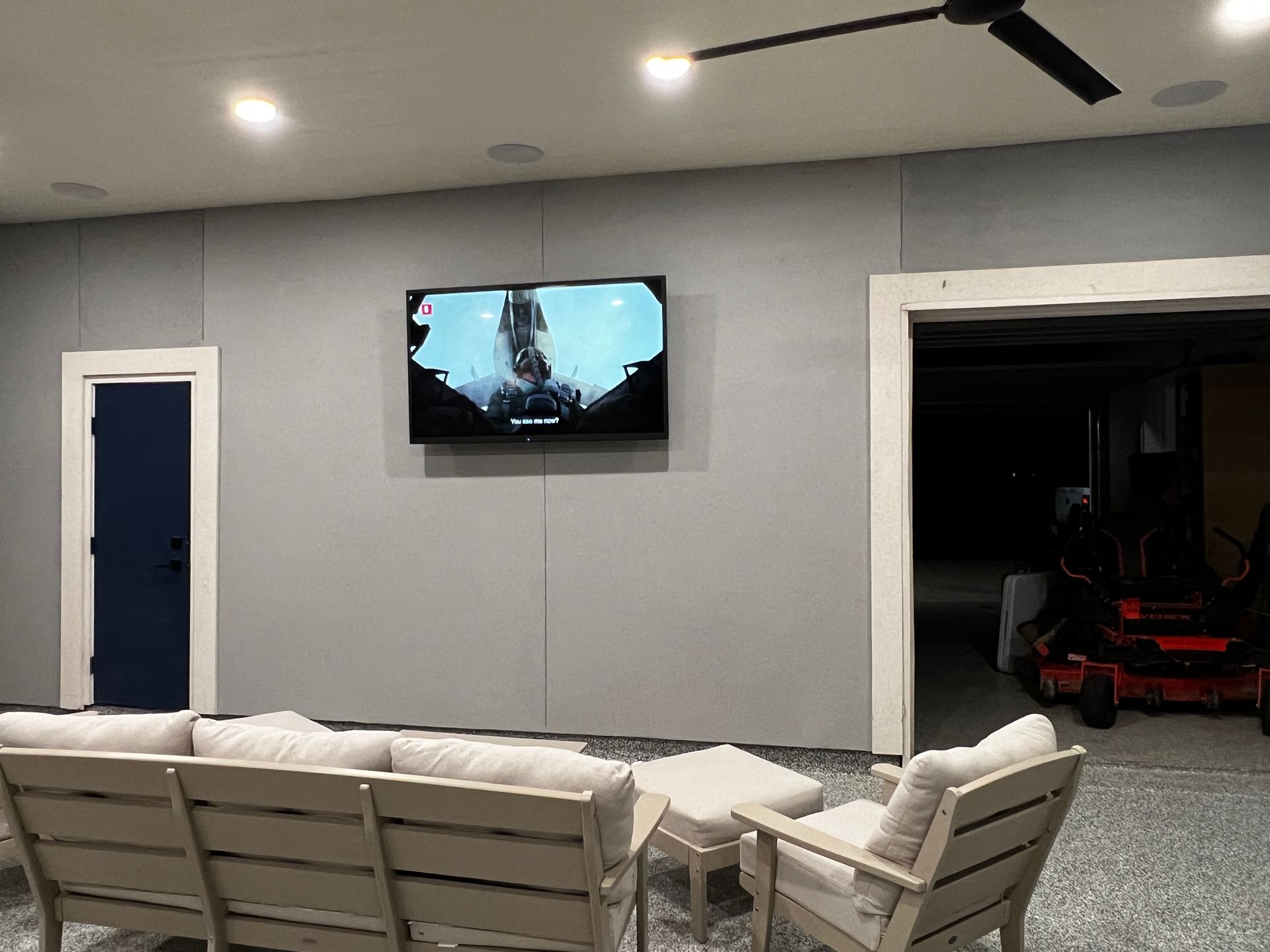 A living room with a couch and chairs and a flat screen tv on the wall.