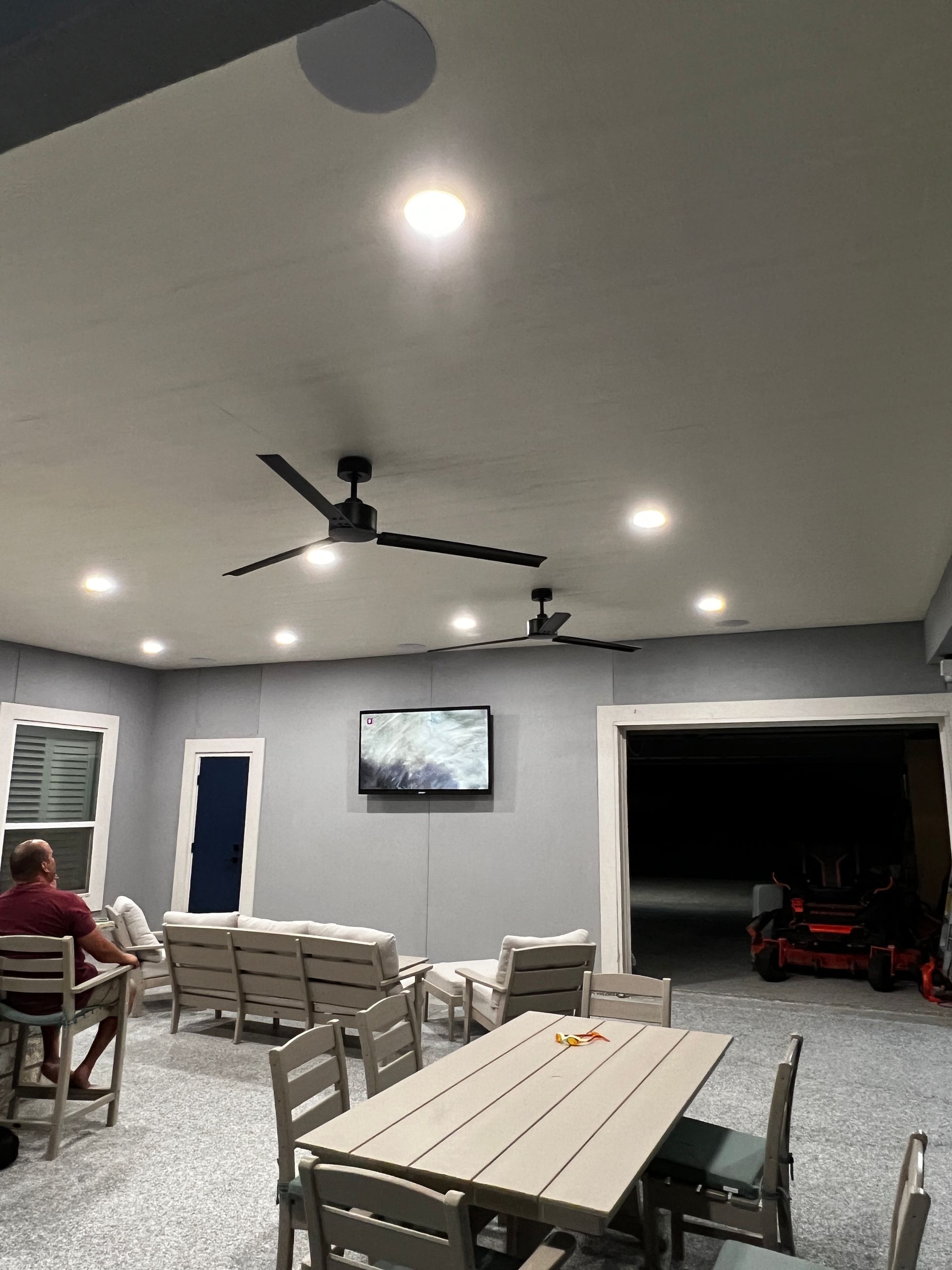 A man is sitting at a table in a room with a ceiling fan.