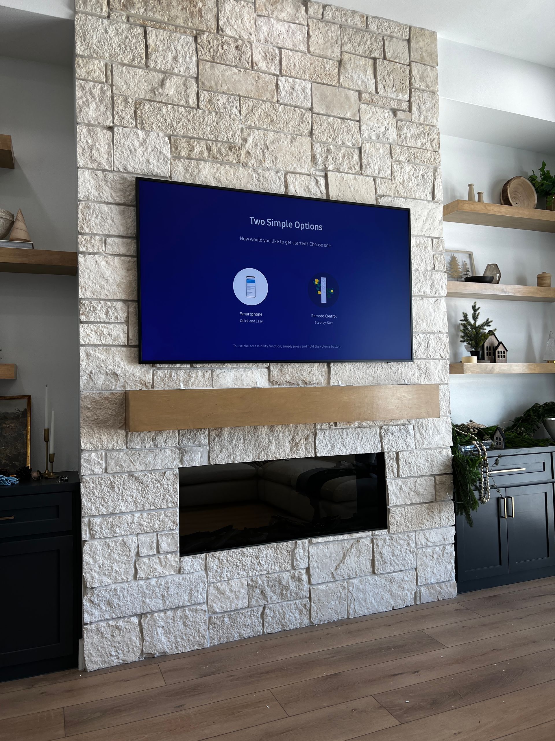 A flat screen tv is mounted on a stone wall above a fireplace.