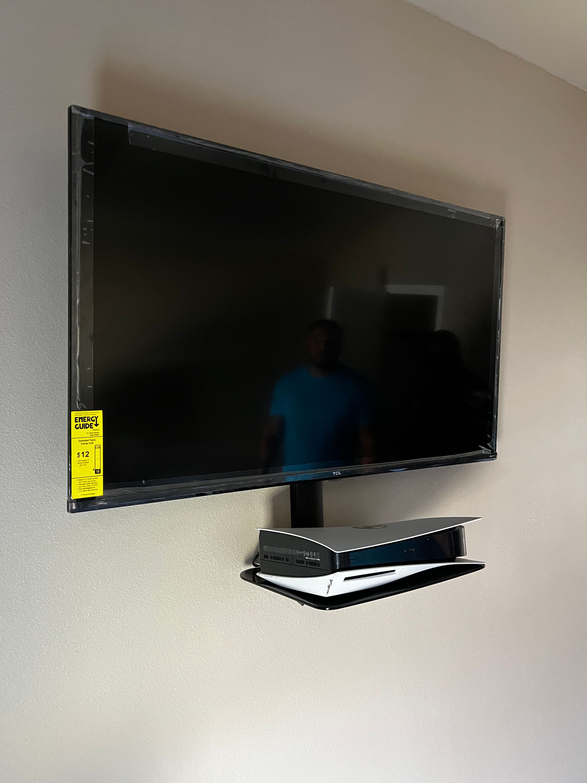 A flat screen tv is mounted on a wall with a shelf underneath it.
