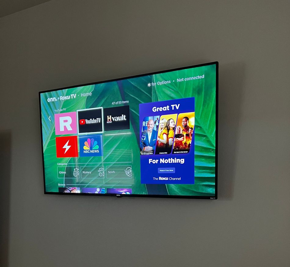 A flat screen tv is hanging on a wall and shows a screen that says great tv for nothing