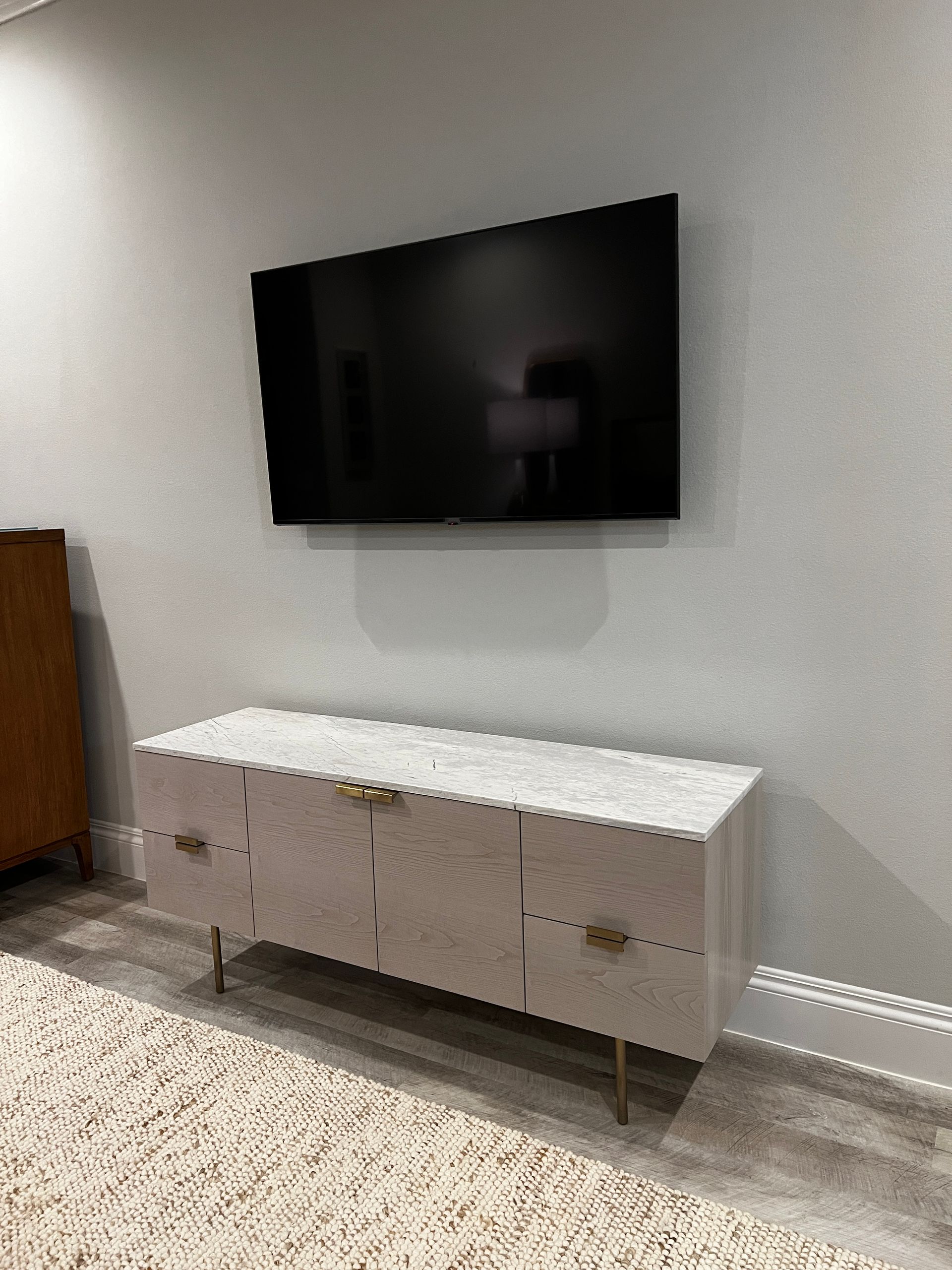 A flat screen tv is mounted on a wall above a white entertainment center.