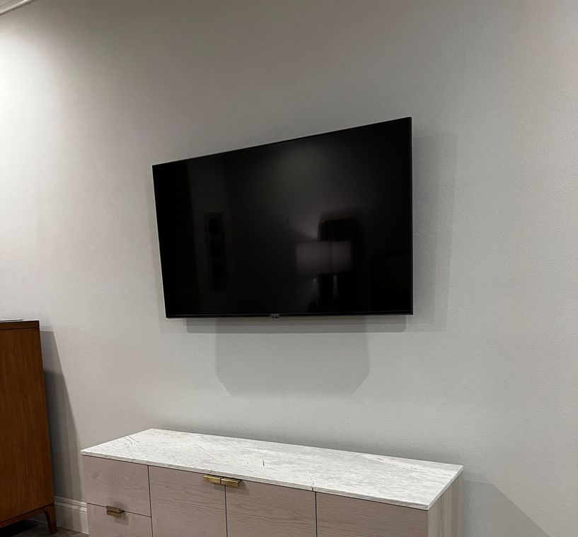 A flat screen tv is mounted on a wall above a dresser.