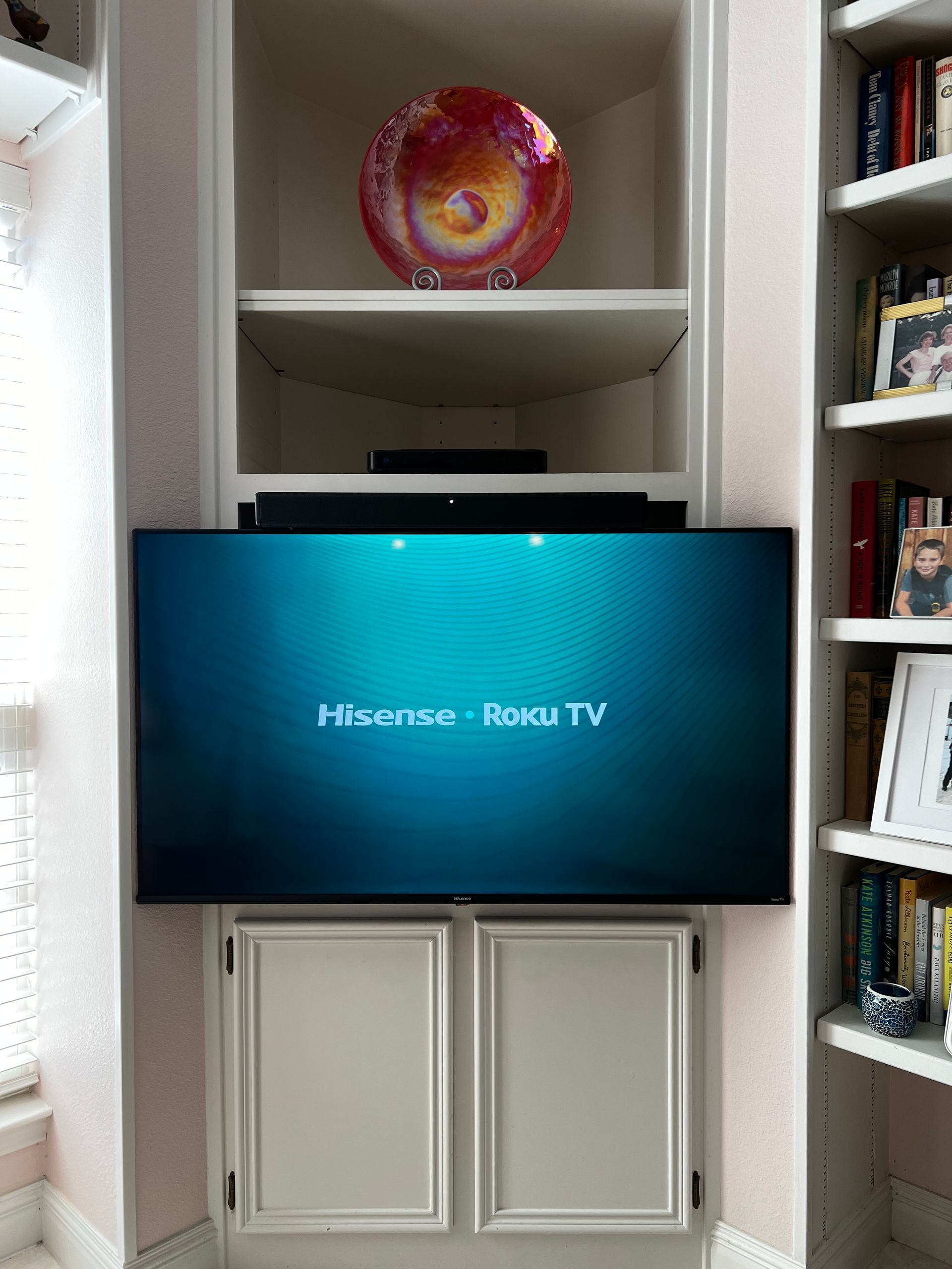 A hisense roku tv is sitting on top of a bookshelf.