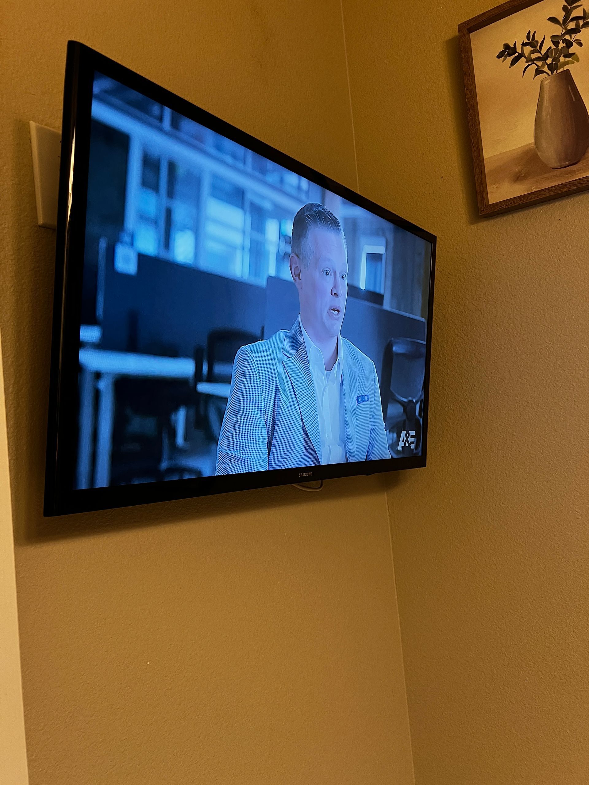 A flat screen tv is hanging on a wall with a man on the screen