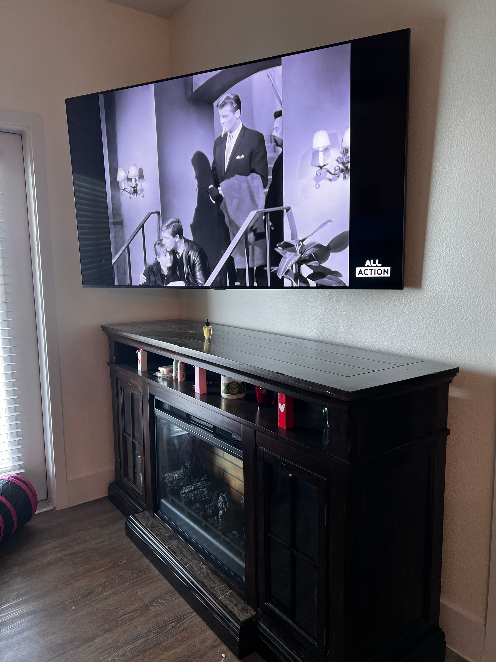 A large flat screen tv is mounted above a fireplace