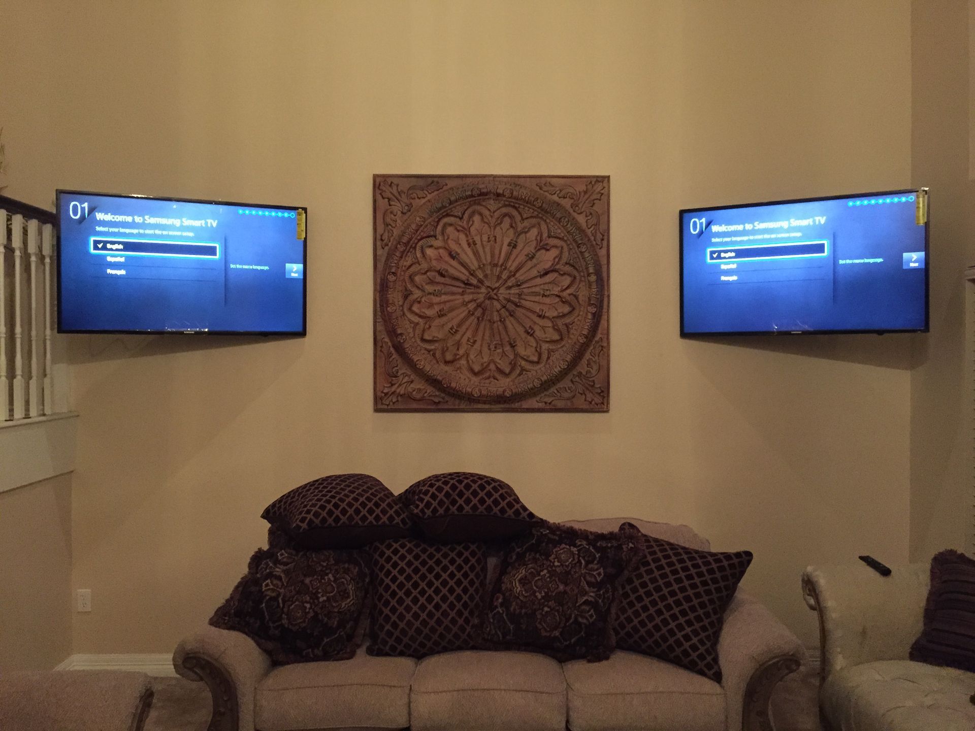 A living room with two flat screen tvs mounted on the wall above a couch.