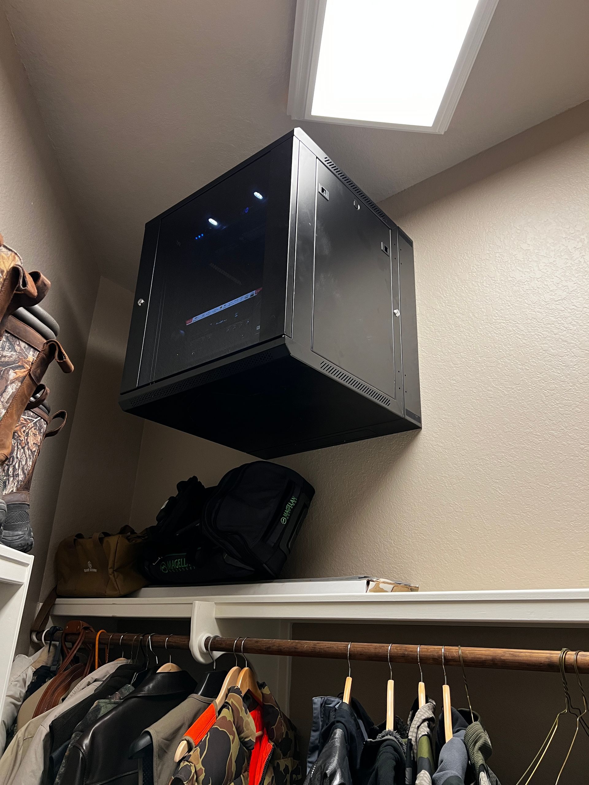 A black box is hanging from the ceiling in a closet.
