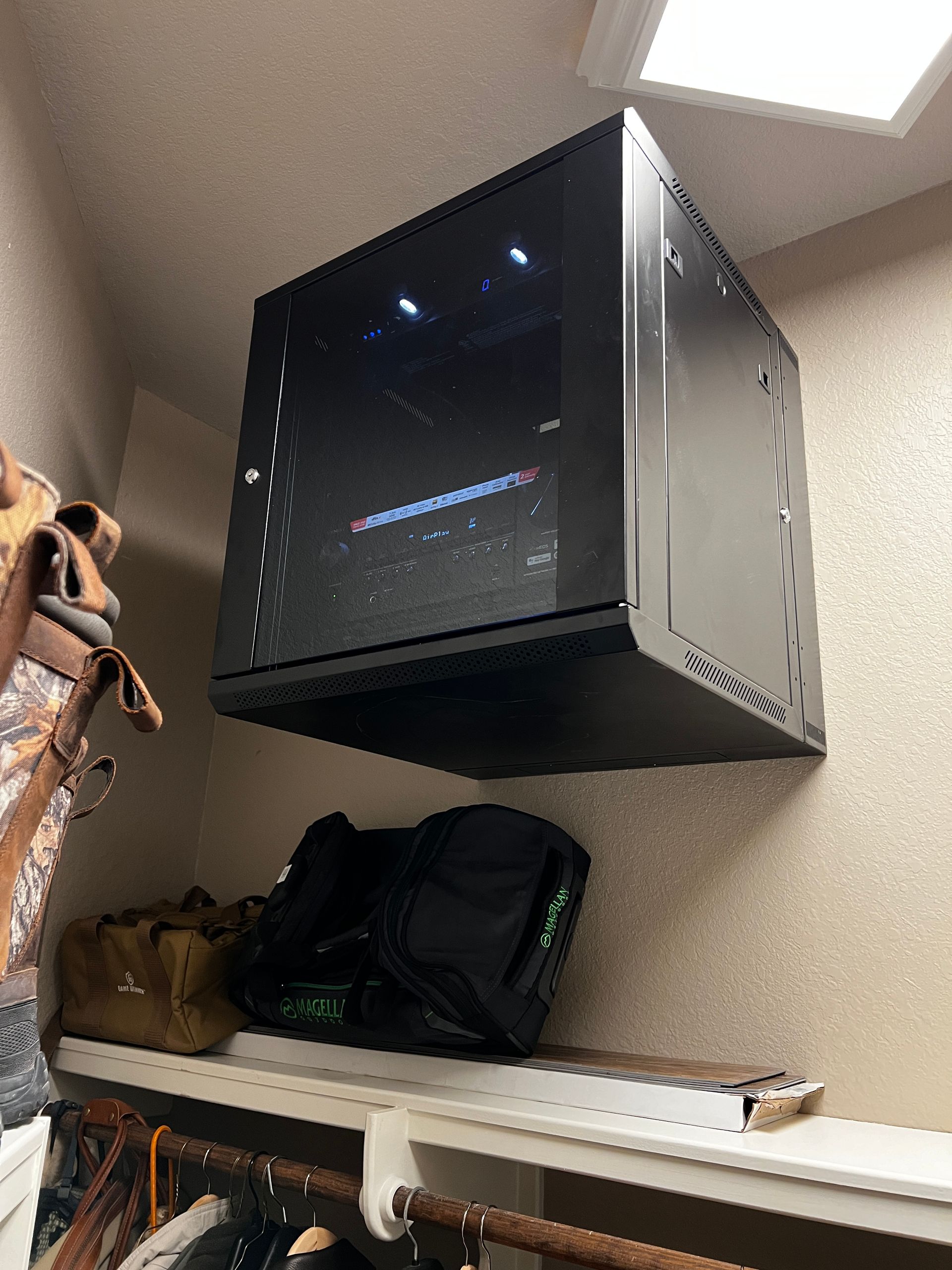 A black box is hanging from the ceiling in a closet.