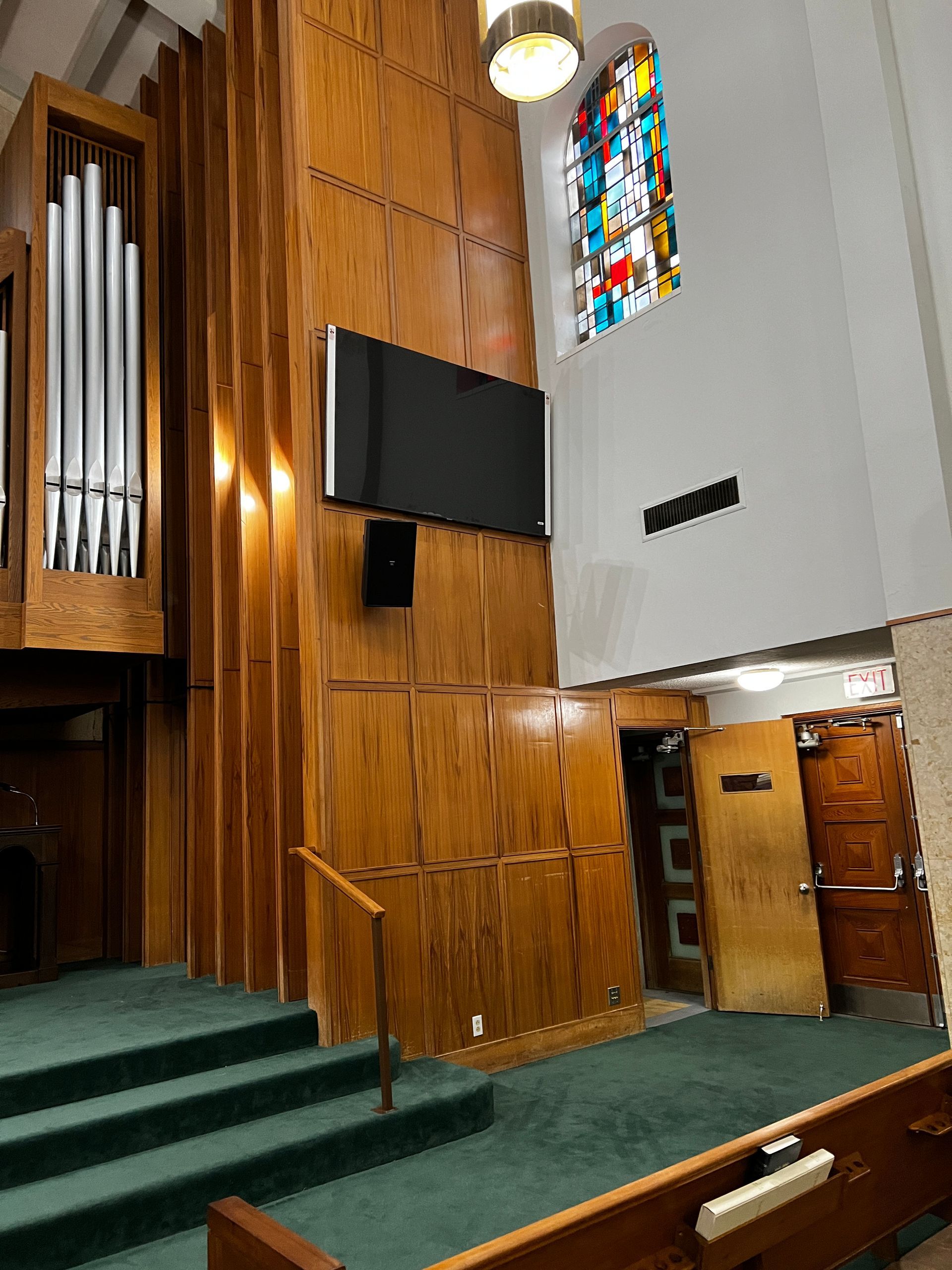 A church with a stained glass window and a pipe organ