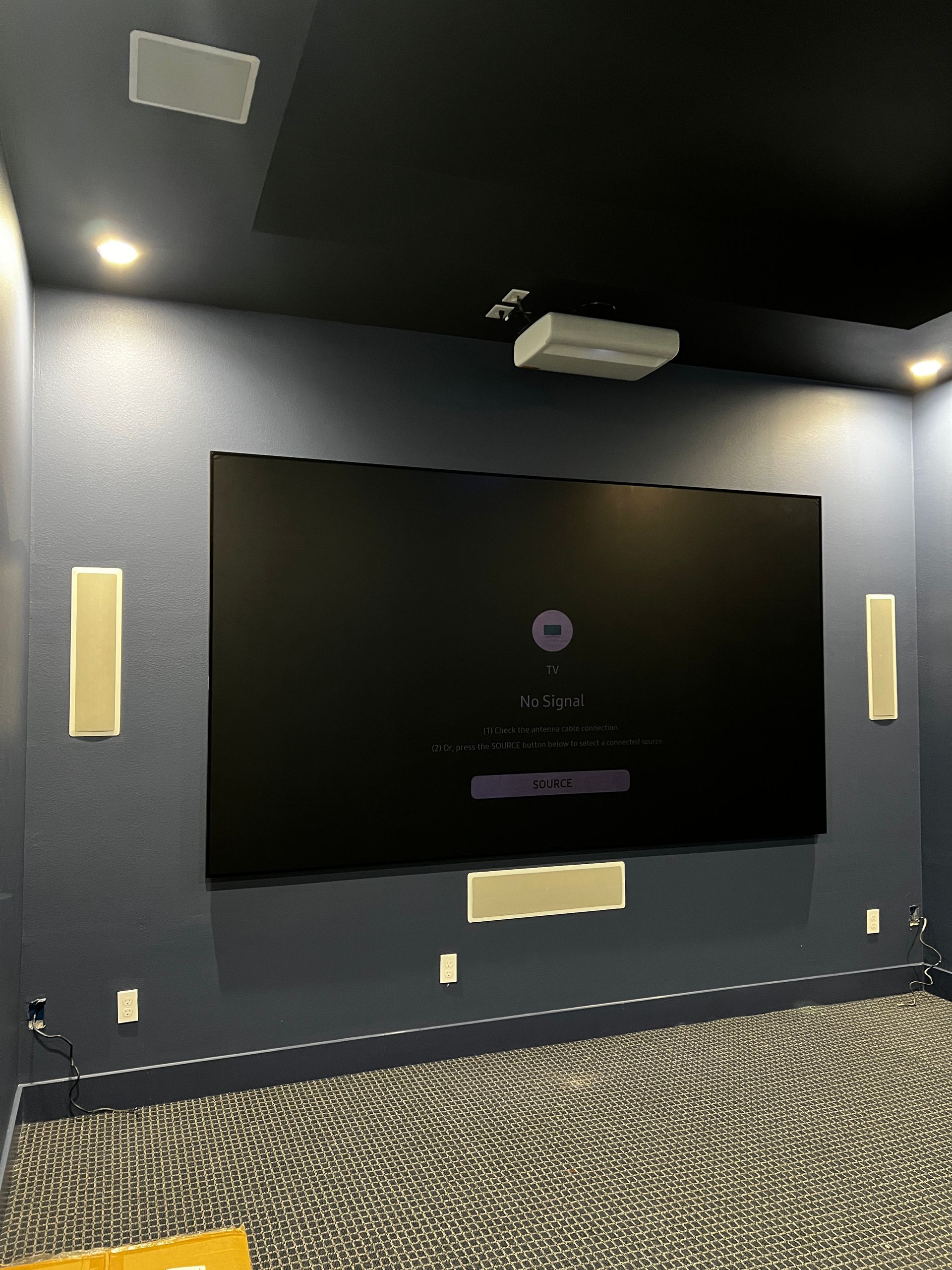 A home theater with a large flat screen tv on the wall