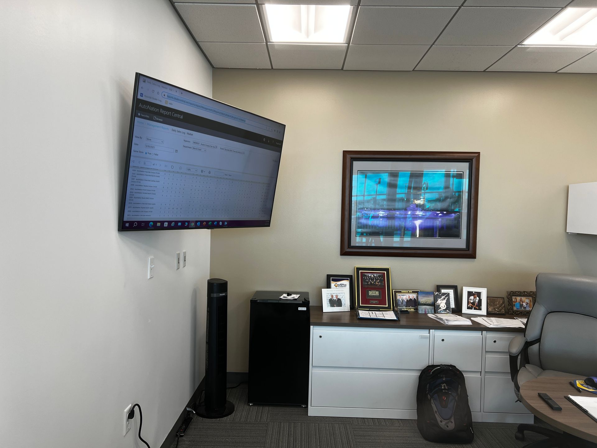 A large flat screen tv is mounted on the wall above a desk.