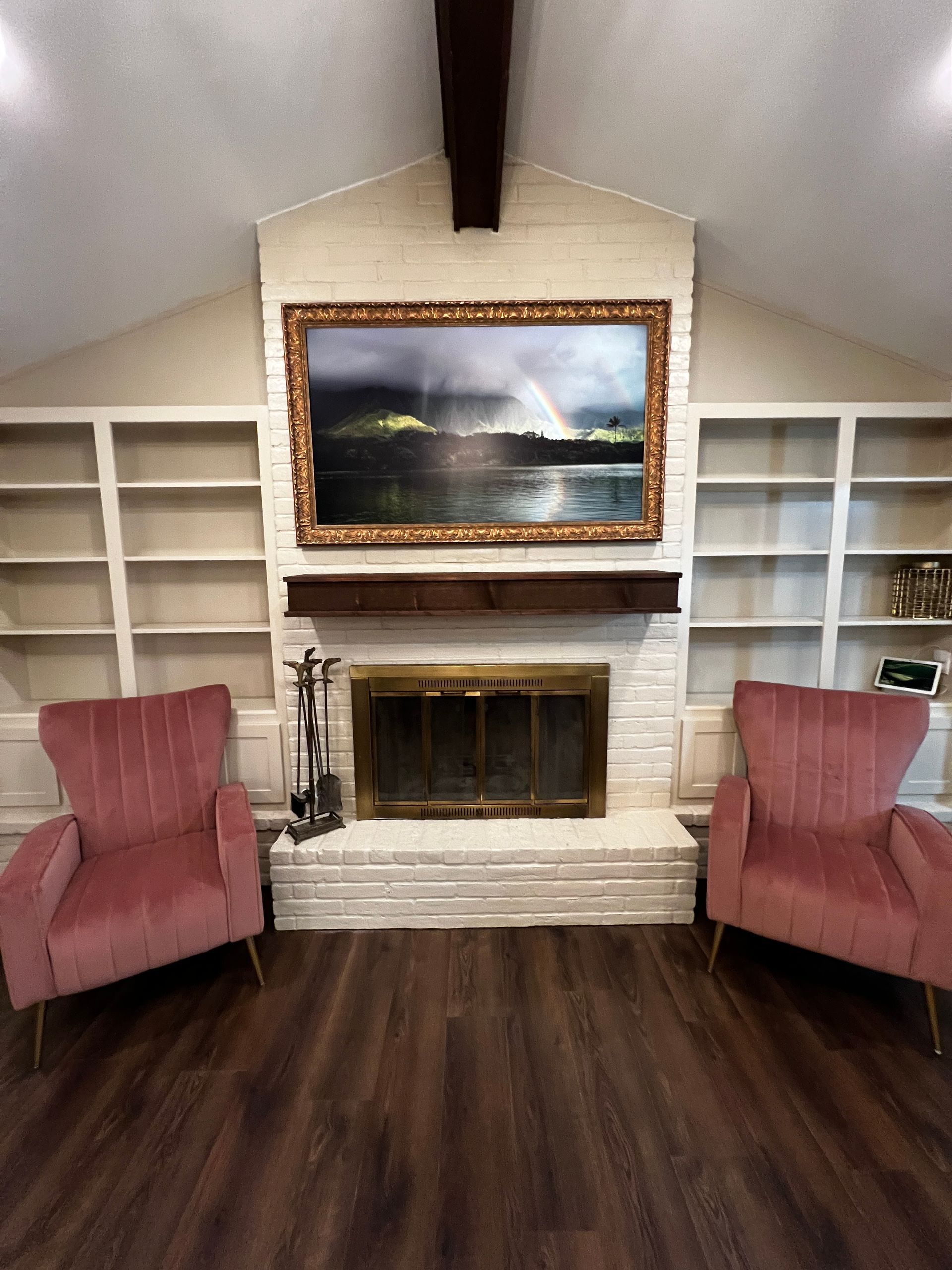 A living room with two pink chairs and a fireplace