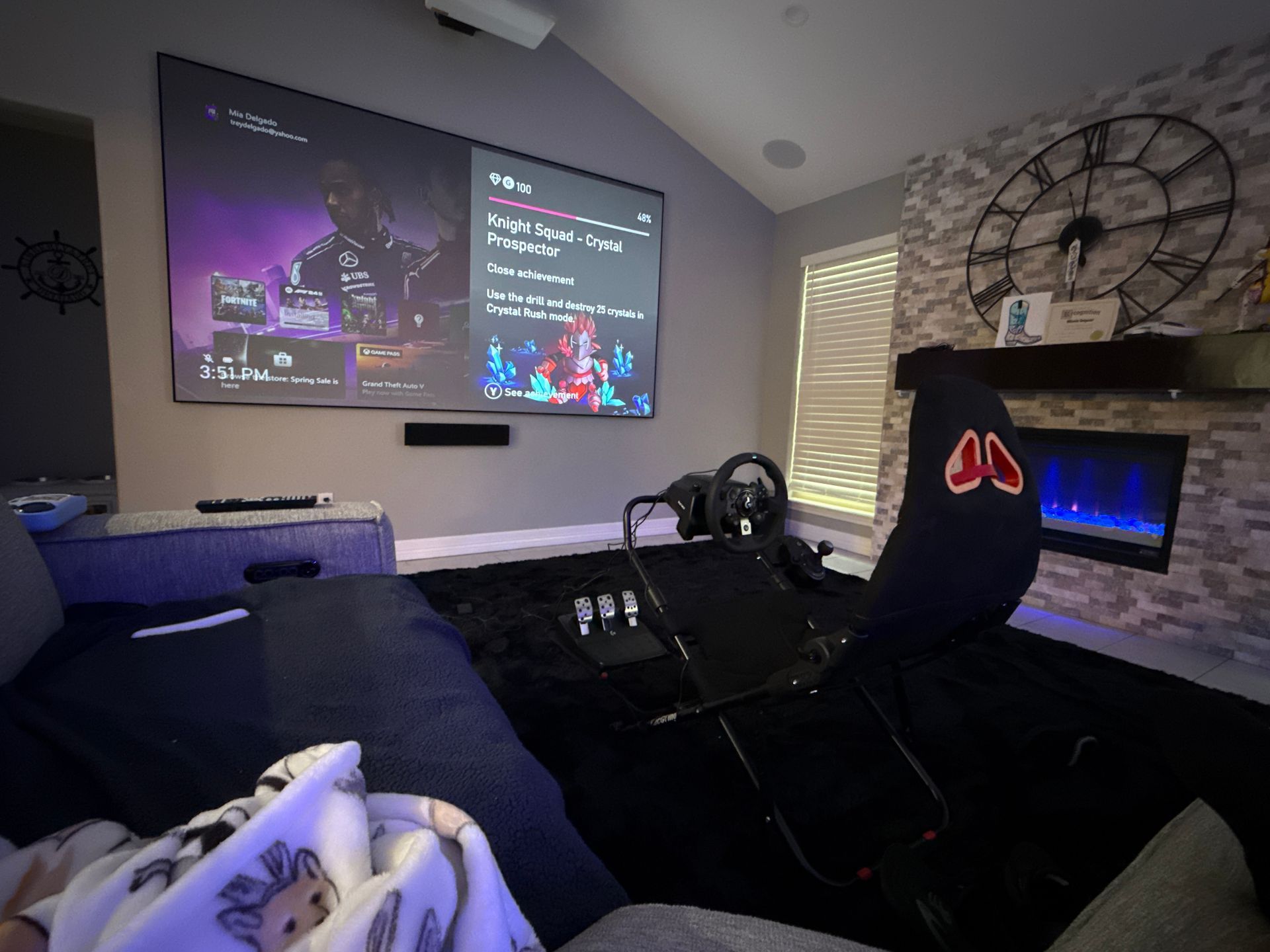A living room with a couch , chair , projector screen and fireplace.