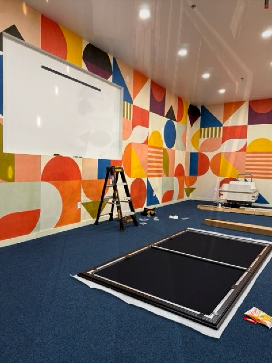 A room with a large projector screen and a ladder