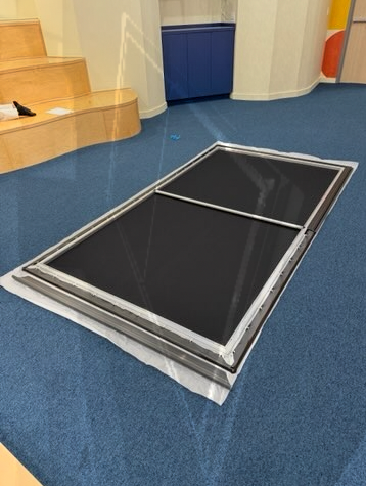 A blue carpeted floor with a black item on it
