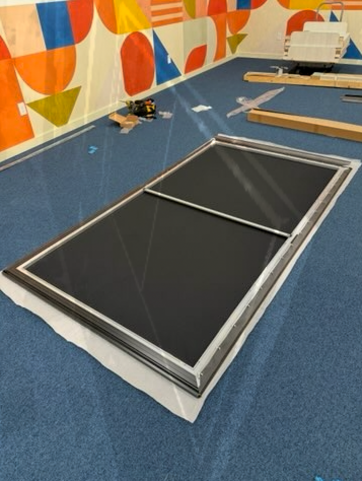 A picture frame is sitting on a blue carpet in a room.