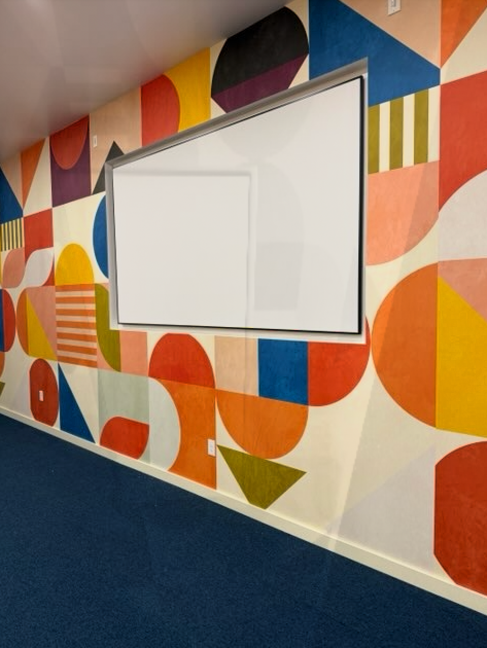 A wall with geometric shapes painted on it and a white board