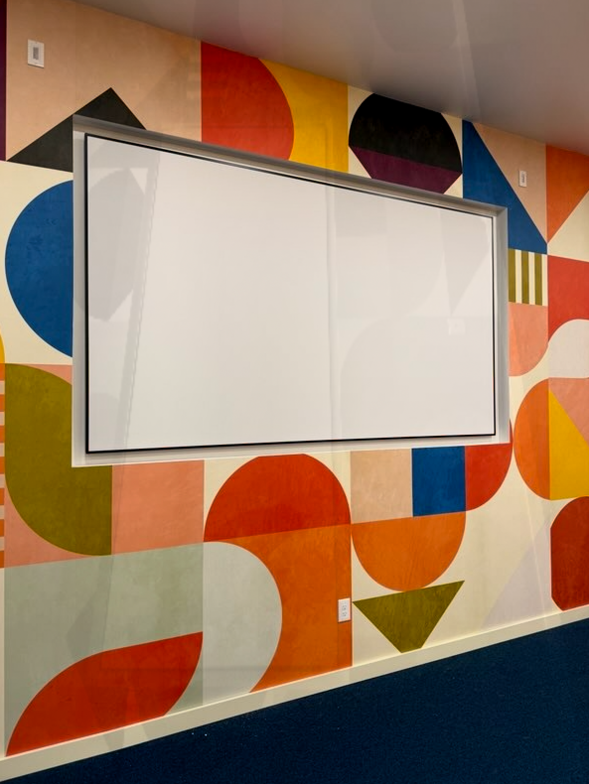 A white board is hanging on a wall with geometric shapes painted on it
