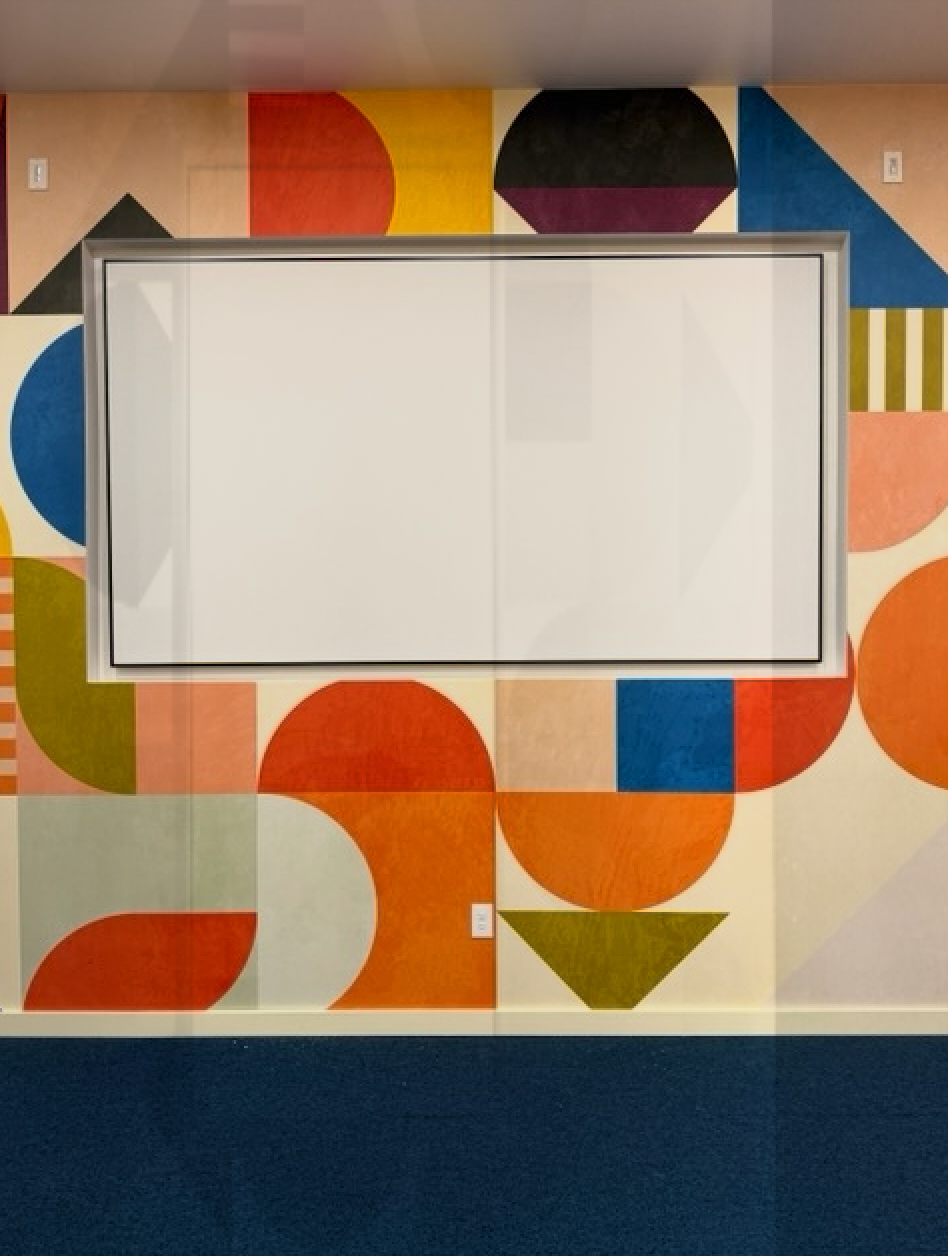 A colorful wall with geometric shapes and a white board
