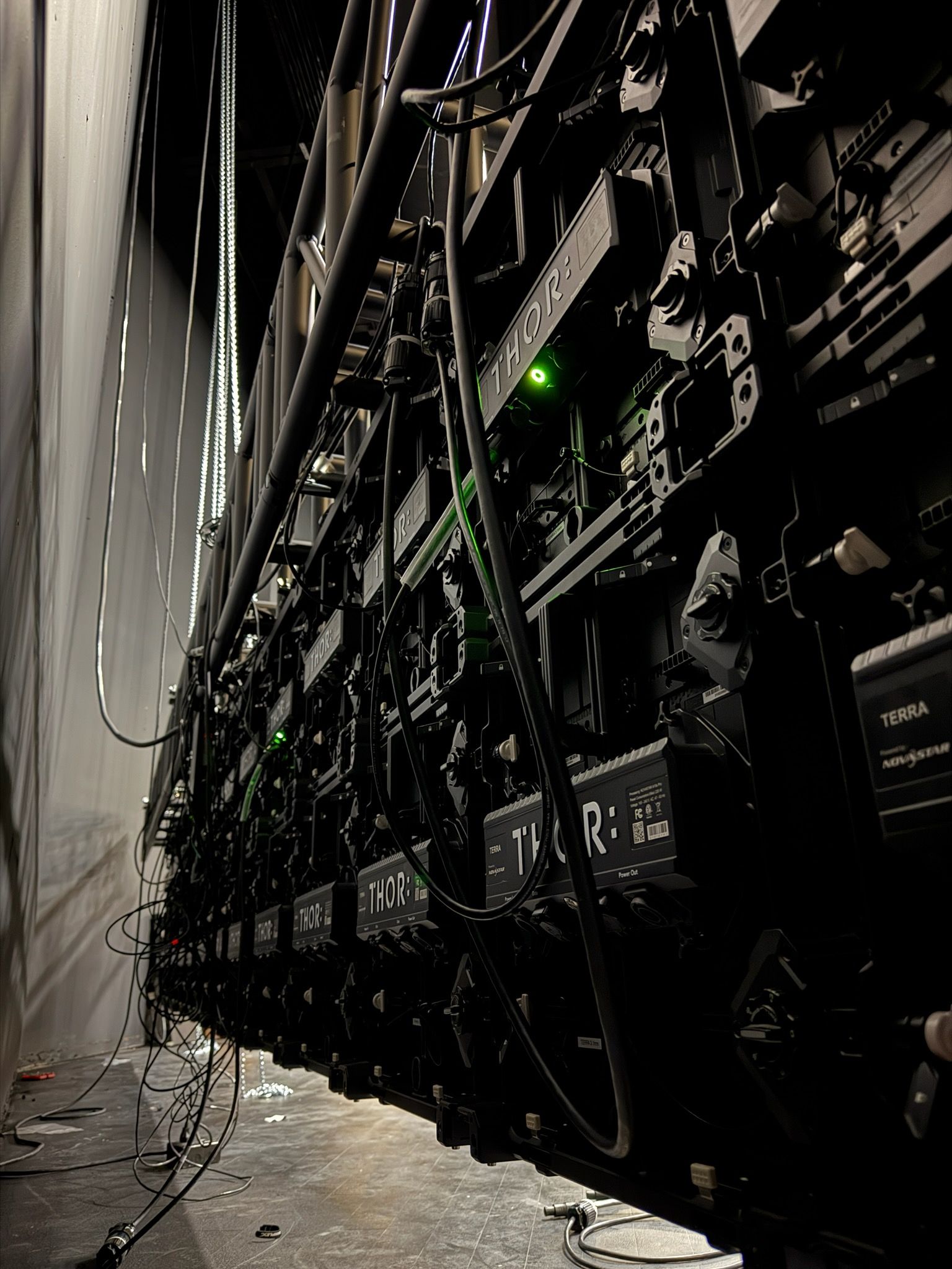 A row of servers are lined up in a dark room.