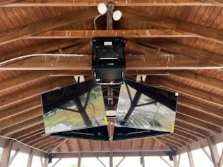 A large mirror is hanging from the ceiling of a wooden structure.