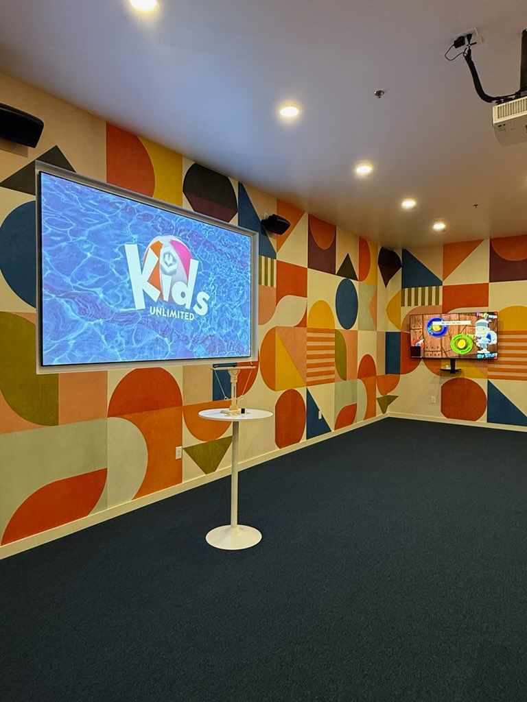 A room with a table and a large screen that says kids on it.