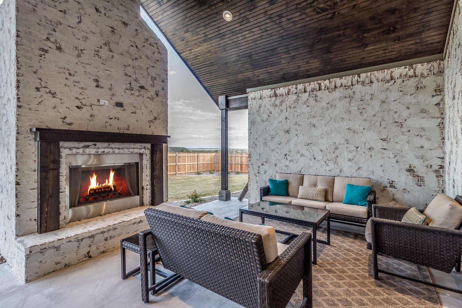 Outdoor patio with fireplace, seating area, and textured stone walls.