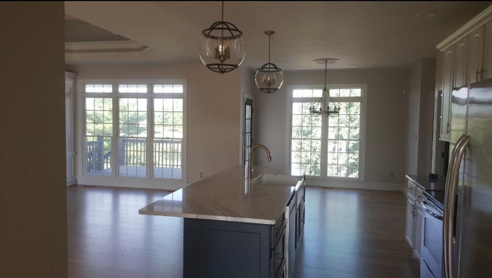 An empty kitchen with a large island and lots of windows