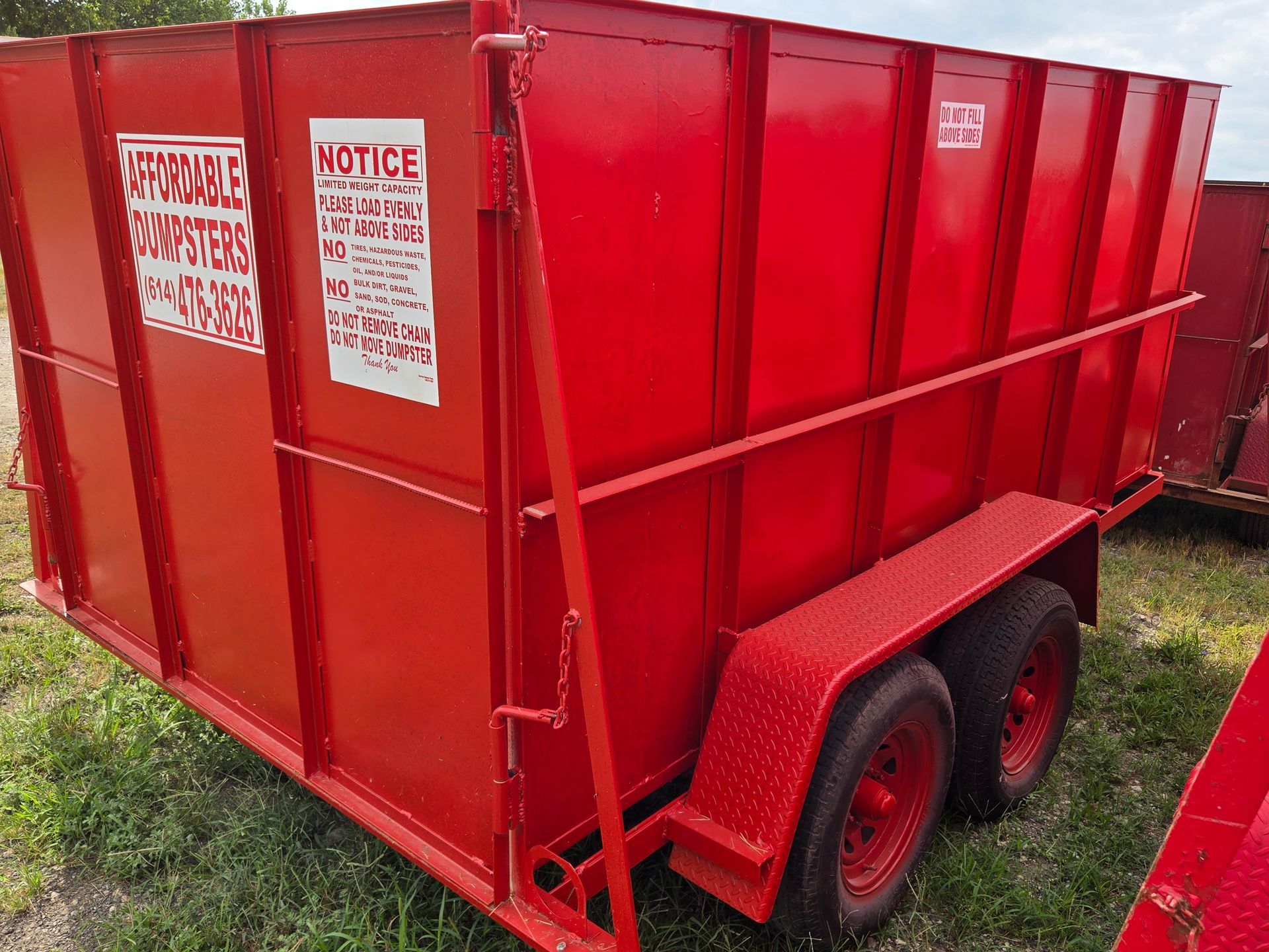 Red dumpster overflowing with construction debris, parked outdoors.