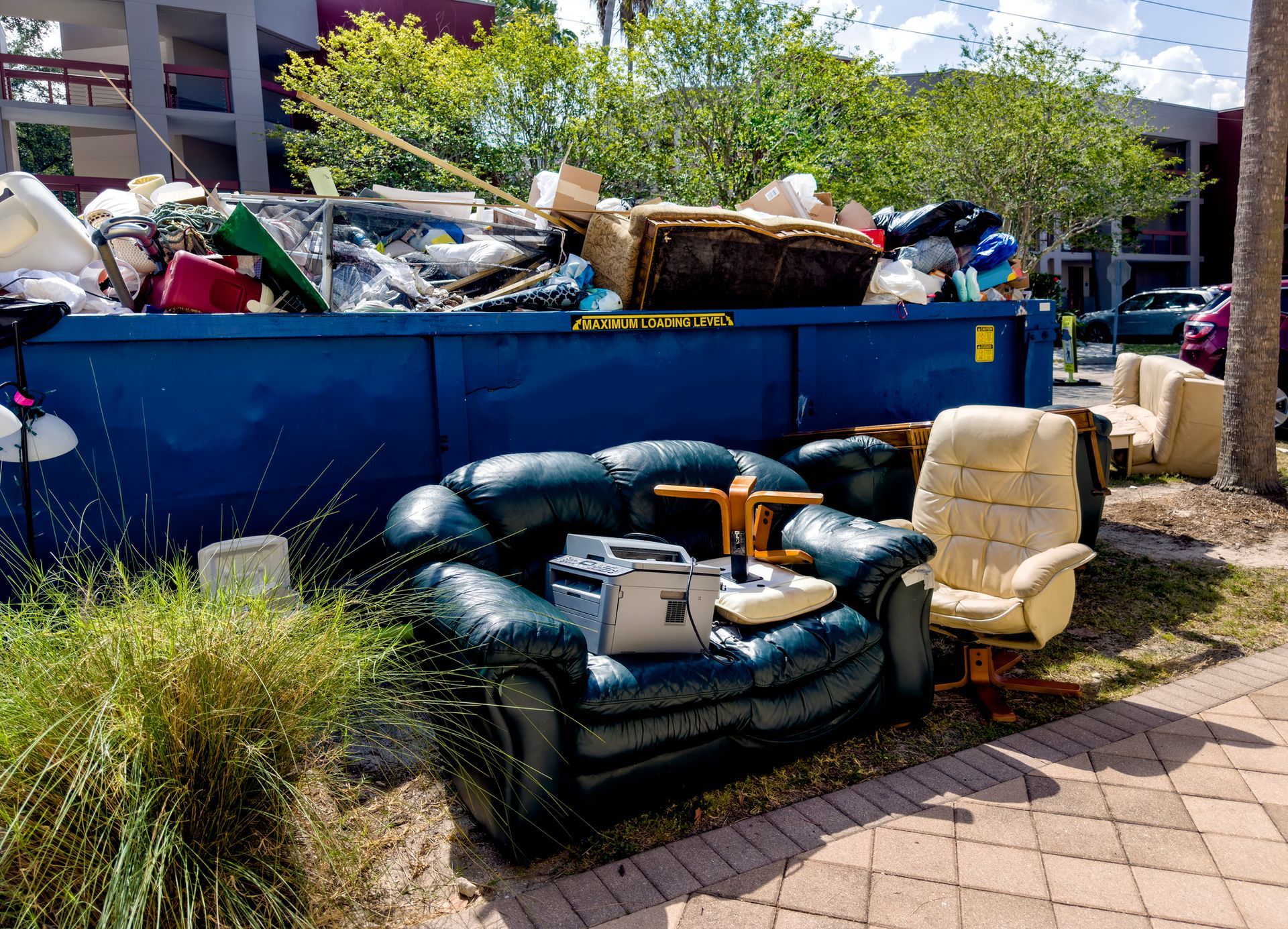 Overflowing roll-off dumpster with assorted garbage from a home cleanout.