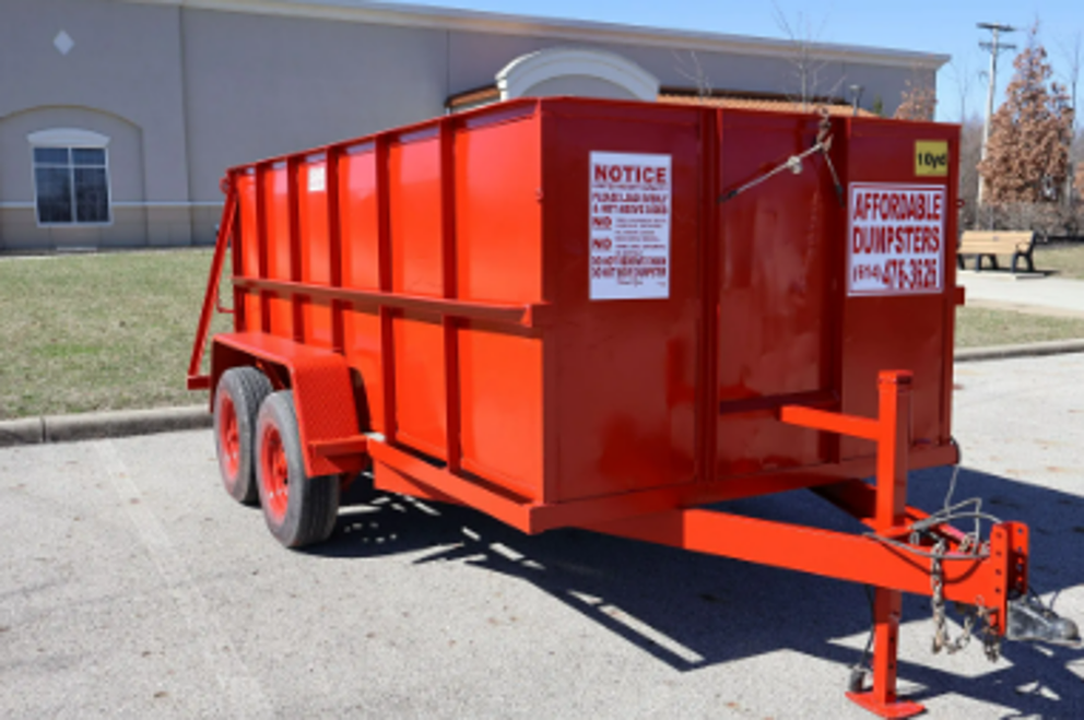 Bright red roll-off dumpster rental trailer parked on a paved lot.