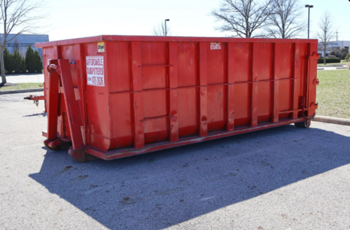 Red roll-off home cleanout dumpster rental container parked outdoors. Red roll-off home cleanout dumpster rental container parked outdoors.