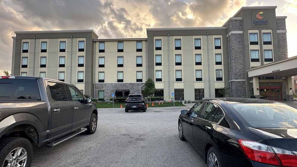 Comfort hotel exterior with cars parked out front under cloudy skies.