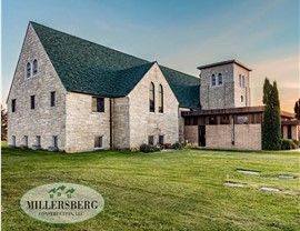 Stone church with green roof and small tower on a grassy lawn.