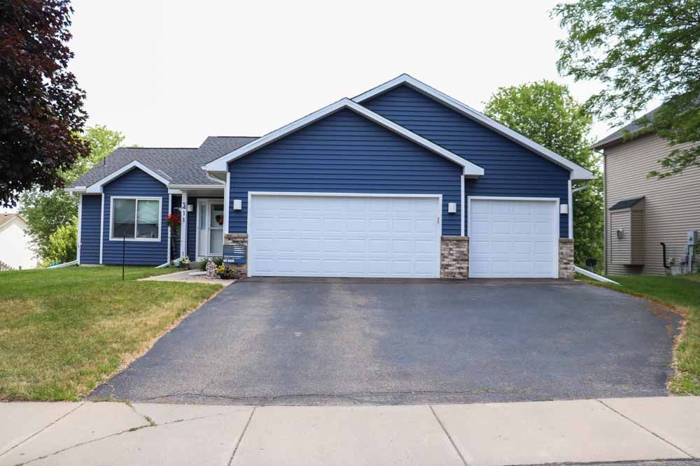 Blue house with two-car garage and asphalt driveway on a cloudy day.