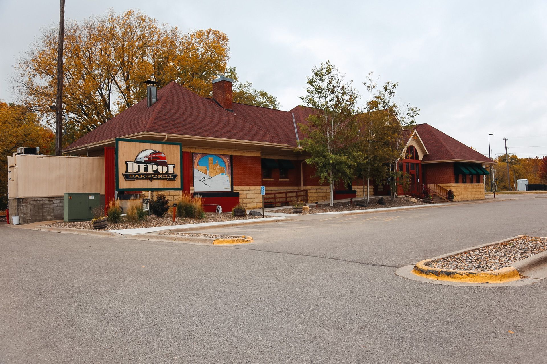 Restaurant exterior with red roof and sign, in a parking lot on a cloudy day.