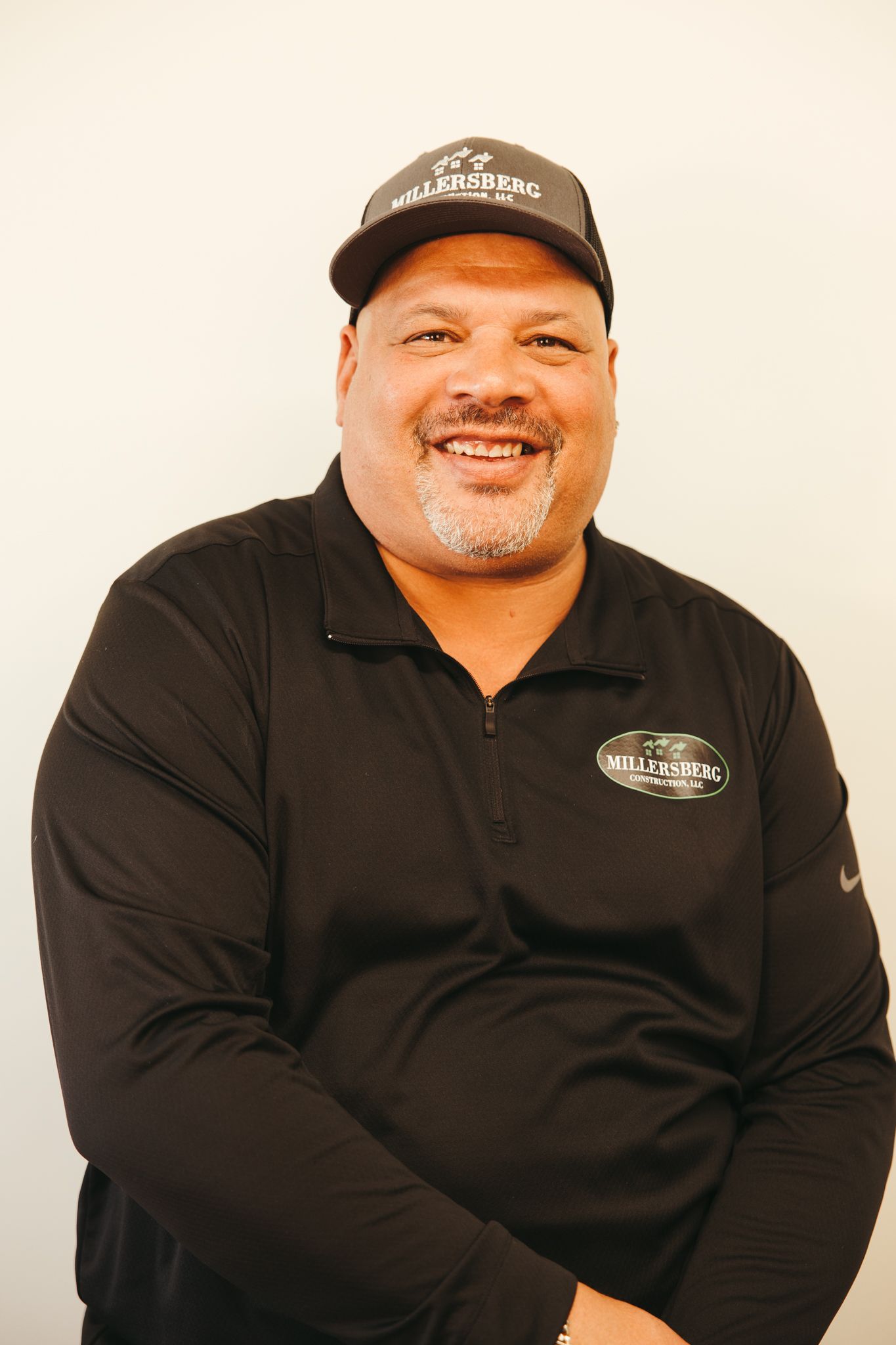 Man wearing a cap and black shirt smiling.