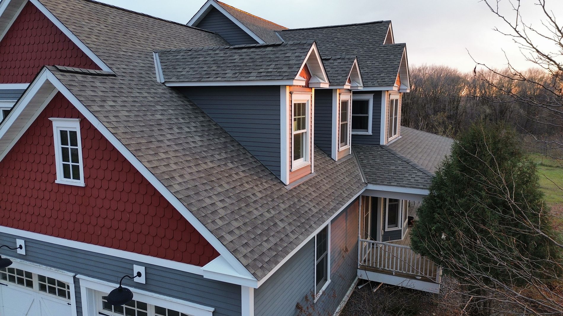 Two-story house with gray and red siding, brown roof, and multiple gabled dormers.