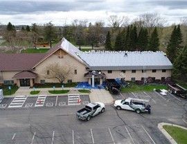Church building with roofing work in progress; trucks and workers on site.