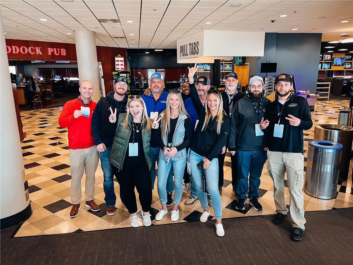 Group of people posing near a bar, some smiling, in a brightly lit venue.